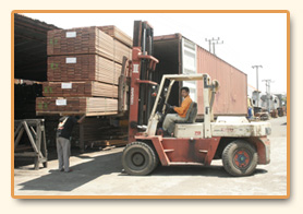 Forklift loading bundled stock into a shipping container.